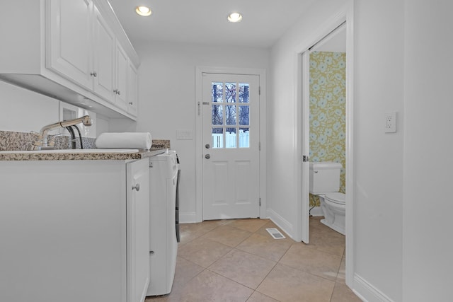 laundry area featuring cabinets, light tile patterned floors, and independent washer and dryer