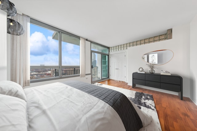 bedroom with floor to ceiling windows, wood-type flooring, and multiple windows