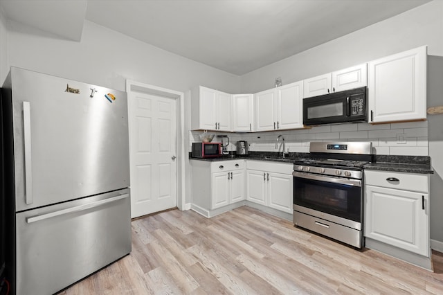 kitchen with backsplash, sink, light wood-type flooring, appliances with stainless steel finishes, and white cabinetry