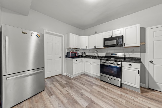 kitchen featuring white cabinets, decorative backsplash, light wood-type flooring, and stainless steel appliances