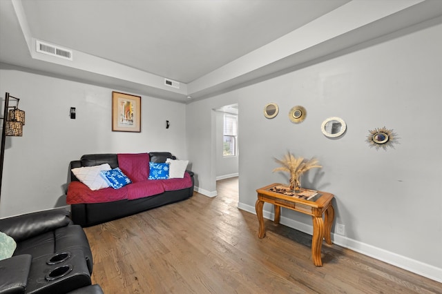 living room with a tray ceiling and light hardwood / wood-style flooring