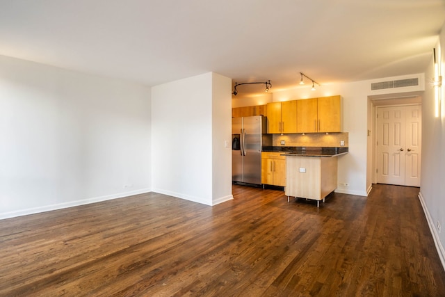 kitchen with stainless steel refrigerator with ice dispenser, dark hardwood / wood-style flooring, track lighting, backsplash, and light brown cabinets