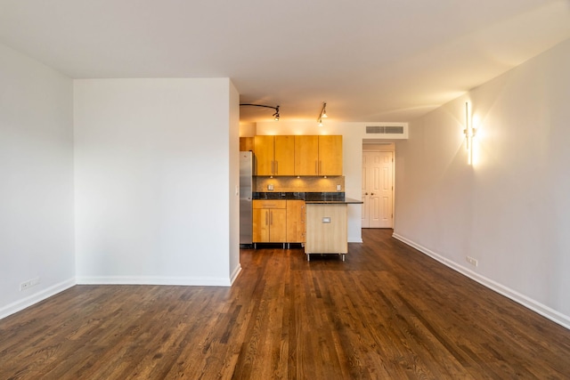 kitchen featuring light brown cabinetry, dark wood-type flooring, and stainless steel refrigerator