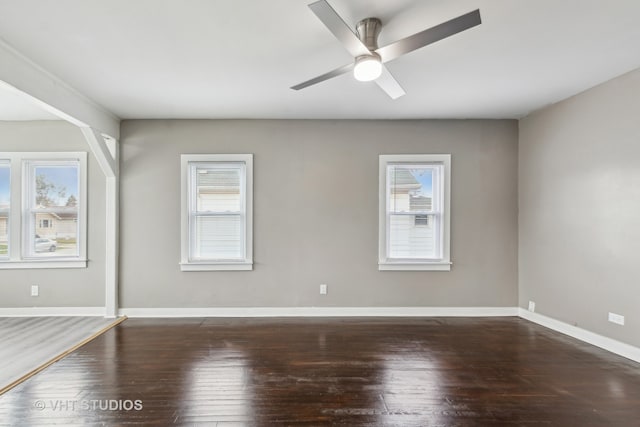 empty room with ceiling fan, plenty of natural light, and dark hardwood / wood-style floors