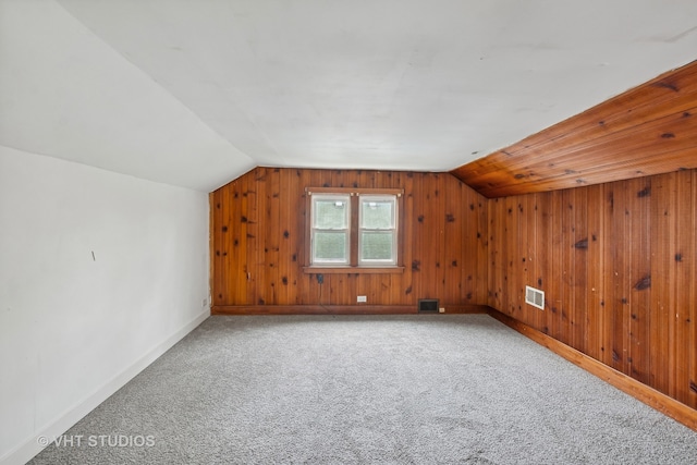 bonus room featuring wooden walls, carpet, and vaulted ceiling