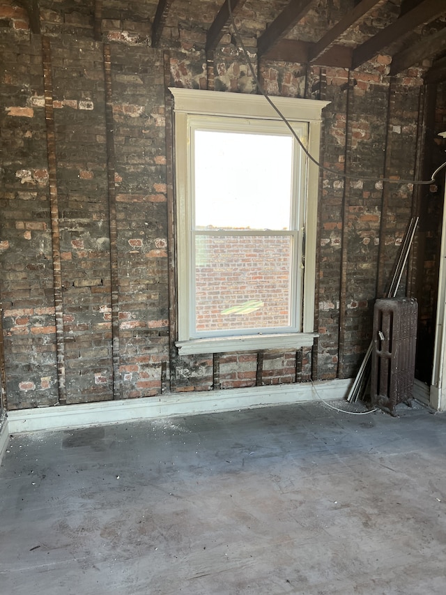 misc room featuring beamed ceiling and concrete flooring