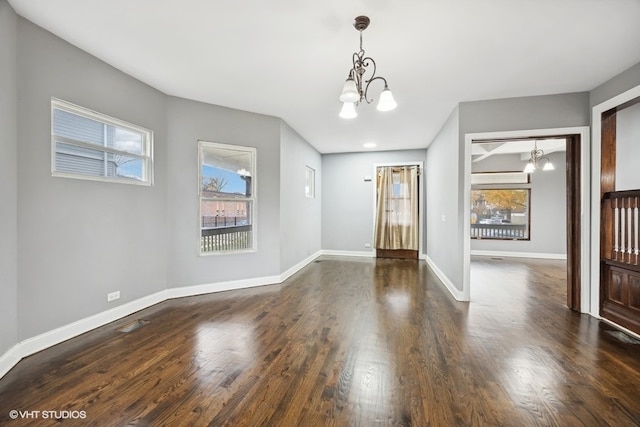 spare room featuring a notable chandelier, dark hardwood / wood-style flooring, and plenty of natural light