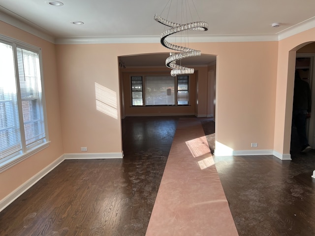 unfurnished dining area featuring crown molding, dark wood-type flooring, and an inviting chandelier