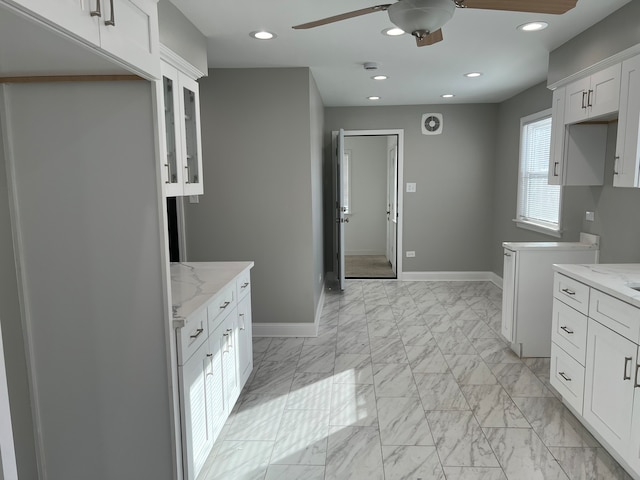 kitchen with white cabinets, light stone counters, and ceiling fan