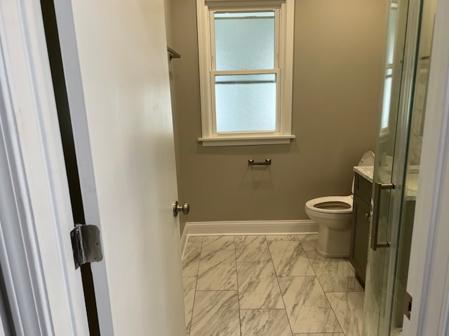 bathroom featuring a shower with shower door and toilet