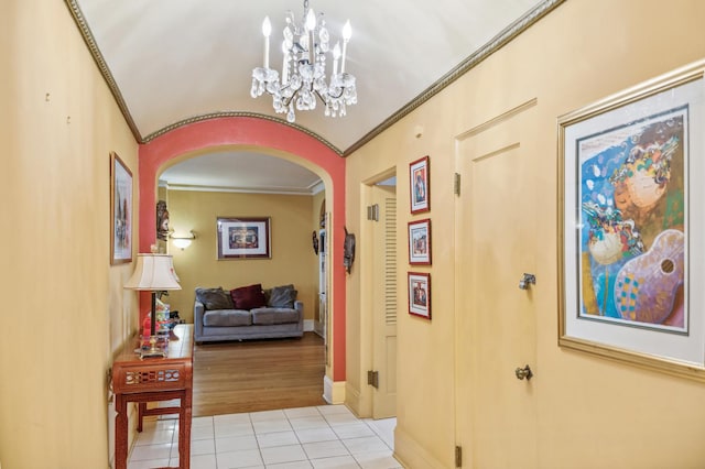 hallway with light wood-type flooring, ornamental molding, and a chandelier