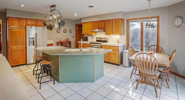 kitchen featuring hanging light fixtures, an island with sink, stainless steel appliances, and light tile patterned floors