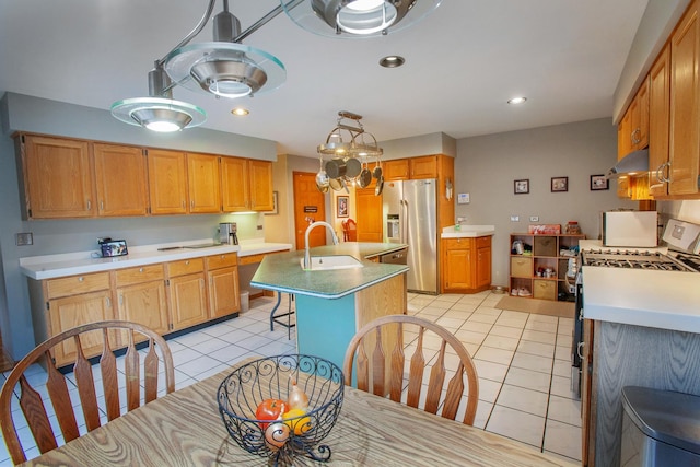 kitchen featuring sink, stainless steel fridge with ice dispenser, an island with sink, white range with gas cooktop, and light tile patterned floors