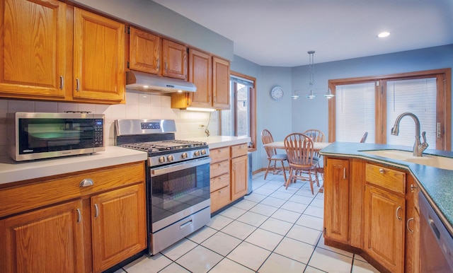 kitchen with decorative backsplash, appliances with stainless steel finishes, sink, light tile patterned floors, and hanging light fixtures