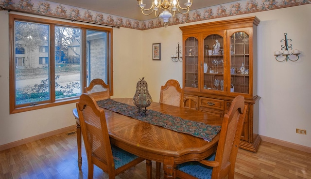 dining area with light hardwood / wood-style floors and an inviting chandelier