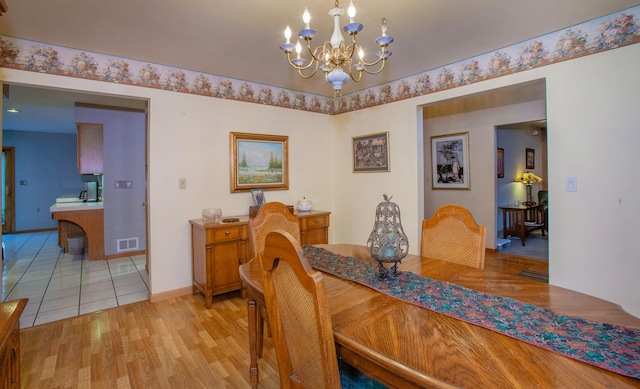 dining space with light hardwood / wood-style flooring and a chandelier