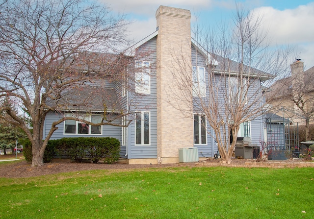 back of house featuring a lawn and central air condition unit