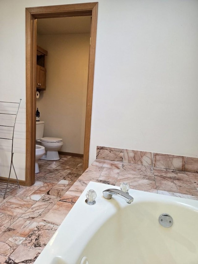 bathroom with a bathtub, toilet, sink, and a bidet