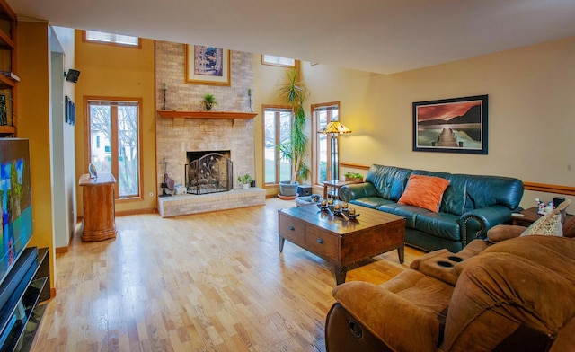 living room with light hardwood / wood-style floors and a brick fireplace