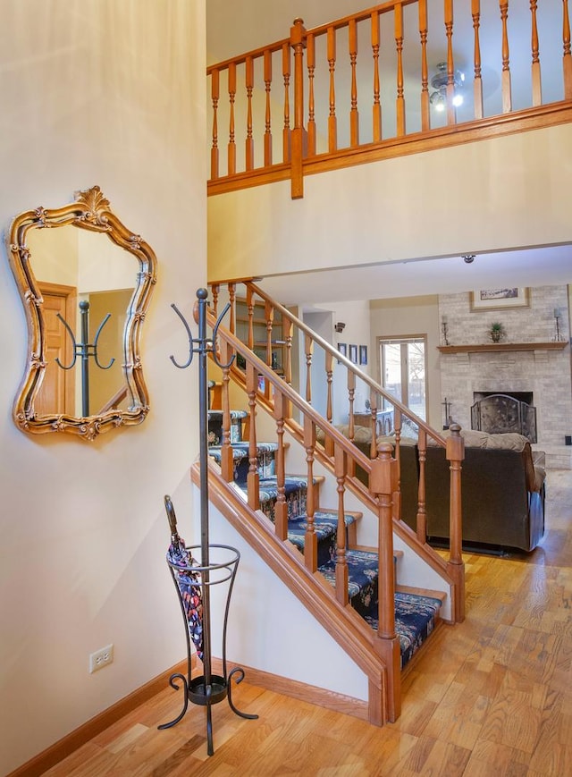 stairs with hardwood / wood-style floors, a fireplace, and a high ceiling