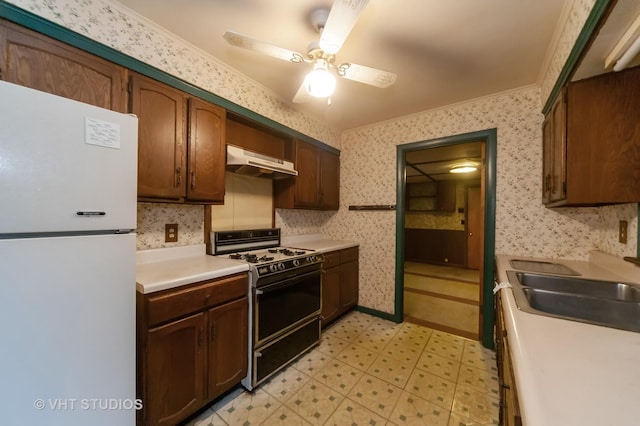 kitchen featuring ornamental molding, black range with gas stovetop, ceiling fan, sink, and white refrigerator