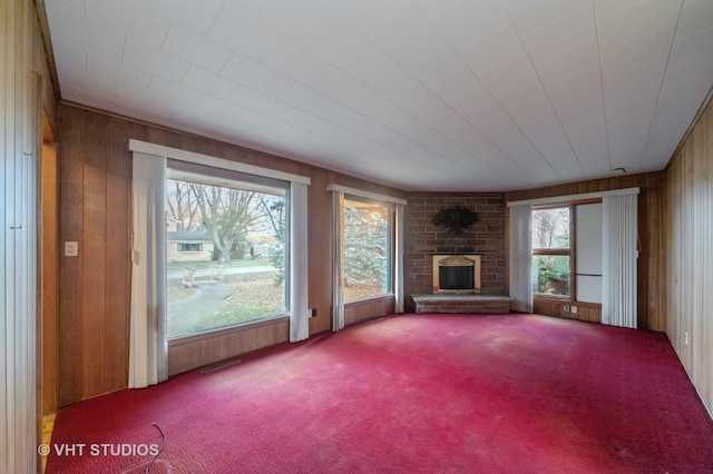 unfurnished living room featuring a fireplace, carpet floors, and wooden walls