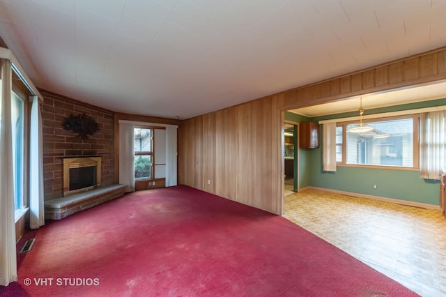 unfurnished living room with a stone fireplace and wood walls