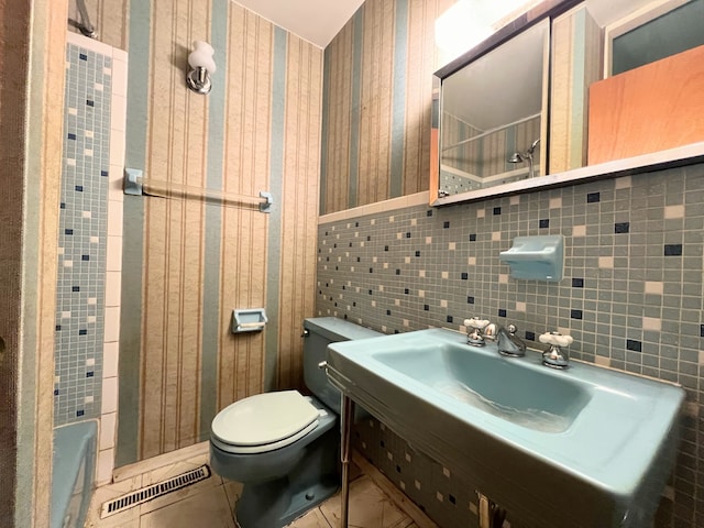 bathroom featuring a shower, toilet, and tile walls