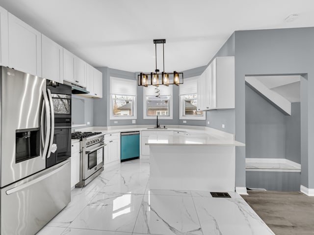 kitchen featuring light stone countertops, appliances with stainless steel finishes, a notable chandelier, white cabinets, and hanging light fixtures