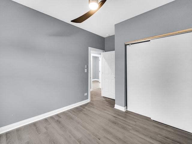 unfurnished bedroom with ceiling fan, wood-type flooring, and a closet