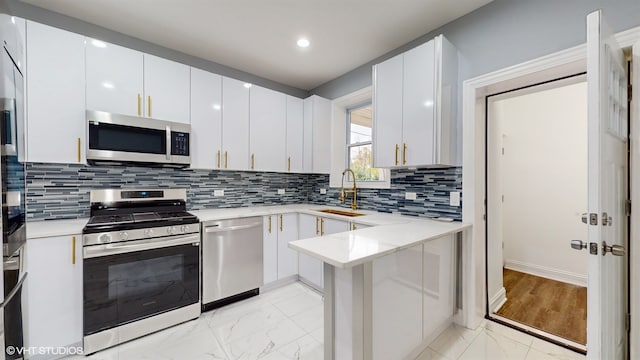 kitchen with sink, stainless steel appliances, backsplash, kitchen peninsula, and white cabinets