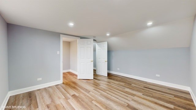 unfurnished bedroom featuring light hardwood / wood-style flooring and lofted ceiling