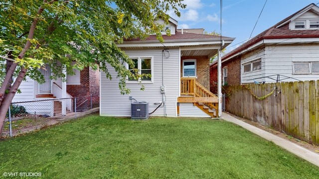 rear view of property featuring a yard and central AC