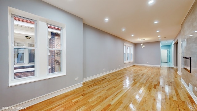 unfurnished living room with light wood-type flooring and a tiled fireplace