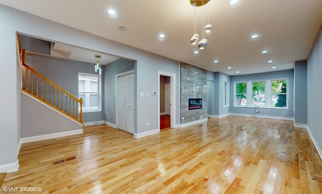 unfurnished living room featuring a tiled fireplace and light hardwood / wood-style floors