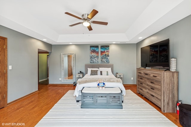 bedroom featuring a tray ceiling, ceiling fan, and hardwood / wood-style floors