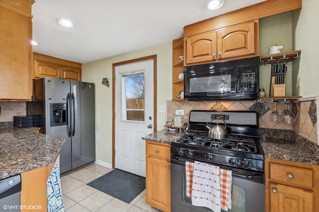 kitchen featuring tasteful backsplash, dark stone countertops, light tile patterned floors, and black appliances