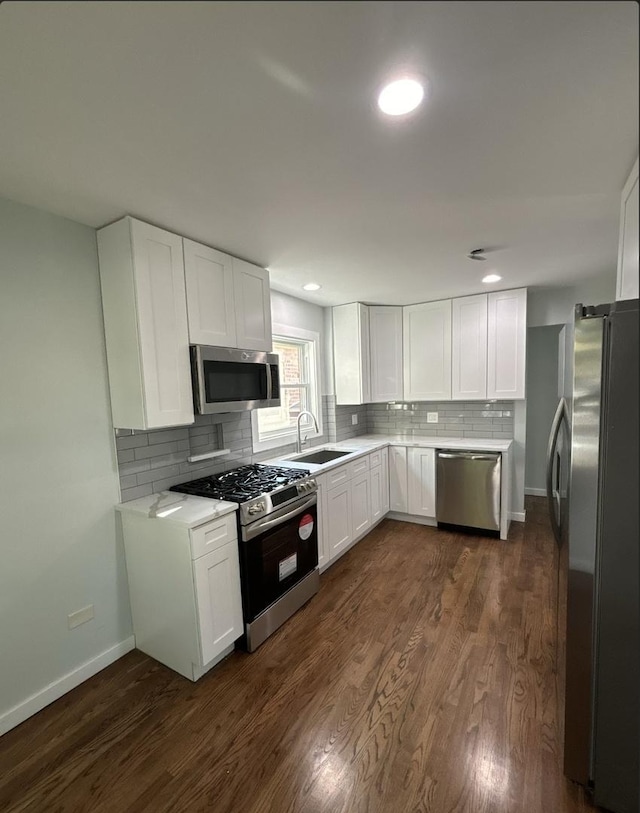 kitchen featuring sink, dark wood-type flooring, decorative backsplash, white cabinets, and appliances with stainless steel finishes