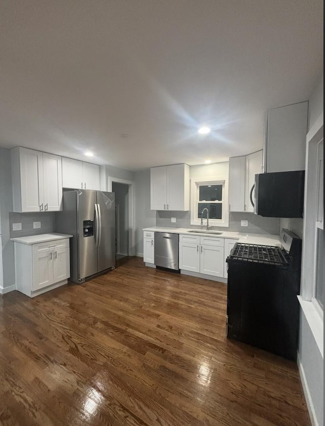 kitchen featuring white cabinets, appliances with stainless steel finishes, dark wood-type flooring, and sink