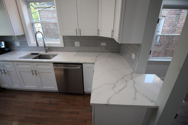 kitchen featuring backsplash, white cabinets, sink, stainless steel dishwasher, and light stone countertops