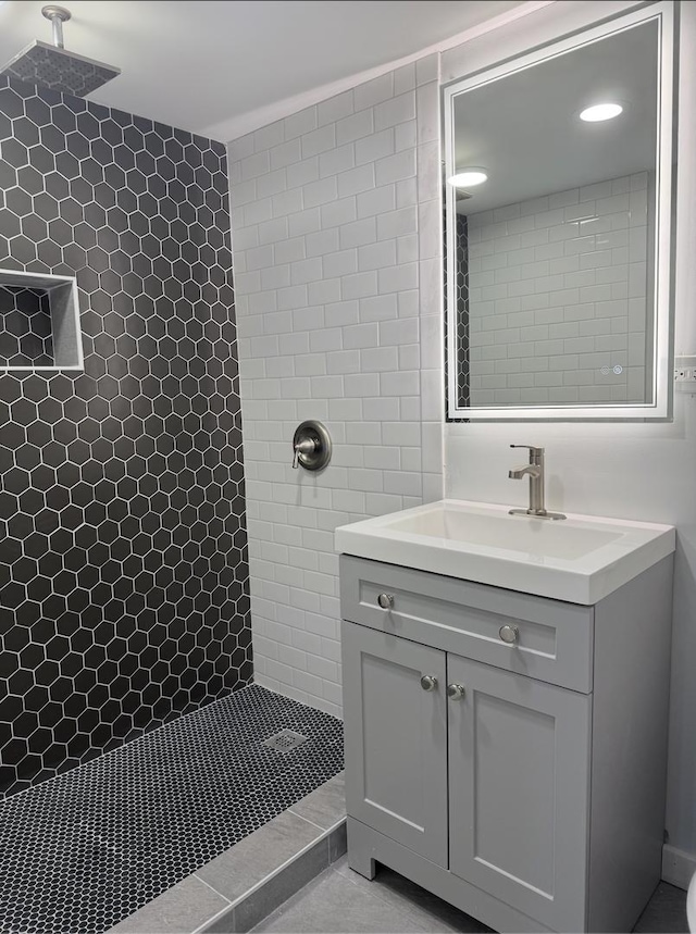 bathroom featuring tile patterned flooring, vanity, and a tile shower