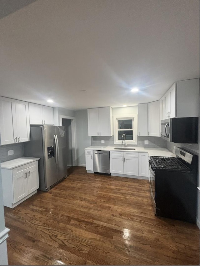 kitchen with appliances with stainless steel finishes, white cabinetry, dark wood-type flooring, and sink