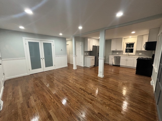 unfurnished living room featuring sink, dark wood-type flooring, and french doors