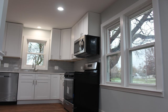 kitchen with decorative backsplash, white cabinetry, sink, and appliances with stainless steel finishes