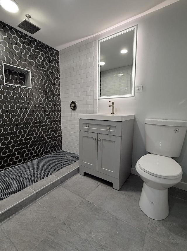 bathroom with vanity, toilet, and tiled shower