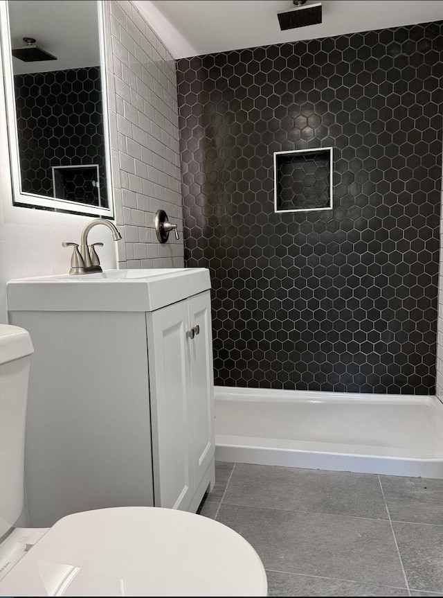 bathroom featuring tile patterned flooring, vanity, toilet, and walk in shower