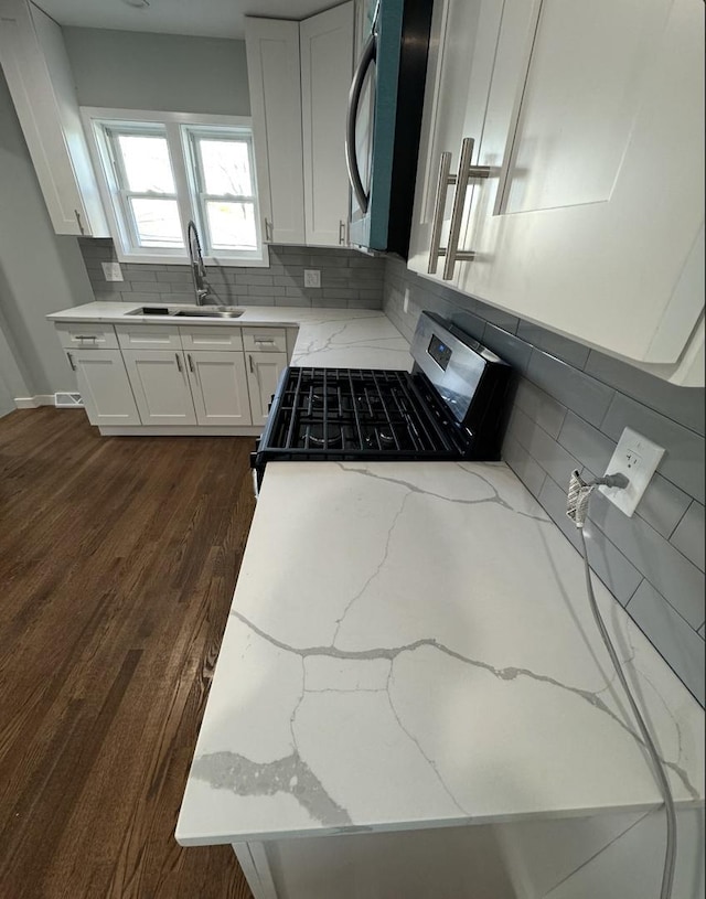 kitchen with white cabinets, black gas range, decorative backsplash, and light stone countertops