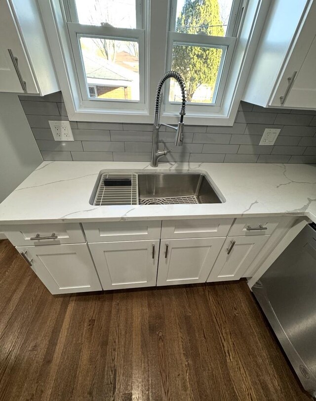 kitchen with white cabinets, dishwasher, light stone countertops, and sink