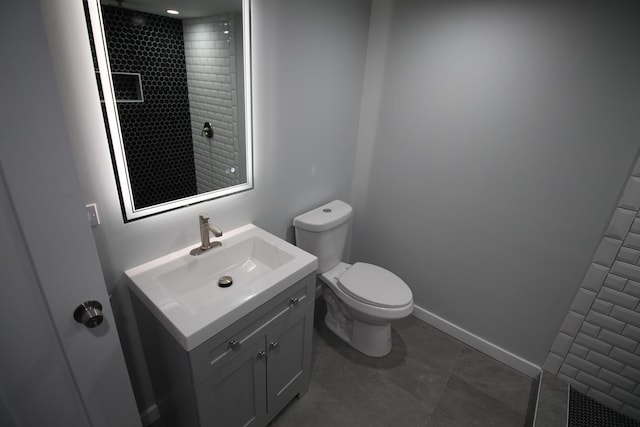 bathroom with tile patterned flooring, a tile shower, vanity, and toilet