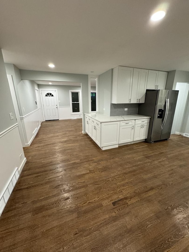 kitchen with stainless steel fridge, tasteful backsplash, a baseboard heating unit, dark wood-type flooring, and white cabinets